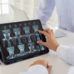 Doctor check up cervical vertebrae spine x-ray image on digital tablet screen with medical team for consult.