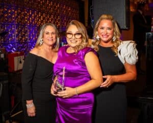 Ximena* (center) receives David K. Hill award at WINGS Purple Tie Ball from Purple Tie Ball Co-Chairs. From left: Debby Jackson, Ximena, and Melissa Canning.