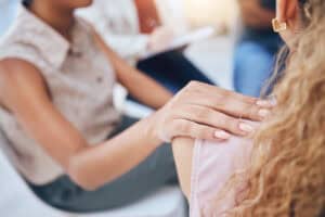 Hand of woman on shoulder, support and teamwork at a seminar, workshop or convention. Worker, employee and girl ready to help, aid or be of service to coworker showing solidarity, unity or union.