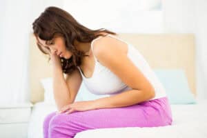 sad woman sitting on her bed at home
